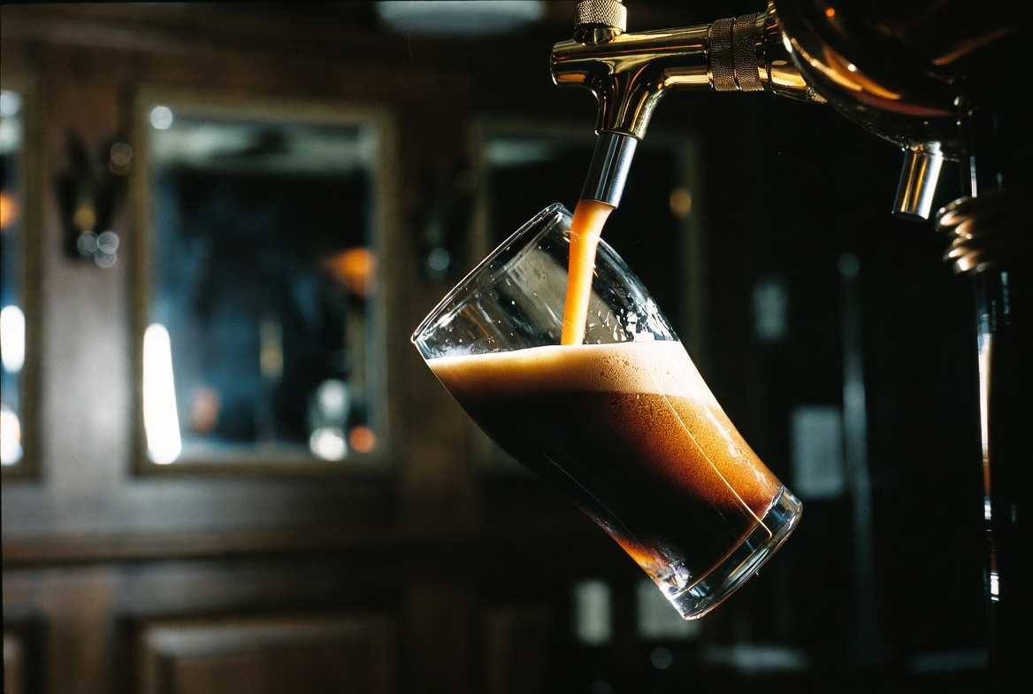 A pint of Guinness mid-pour, dark stout settling beneath a thick cream-coloured head.